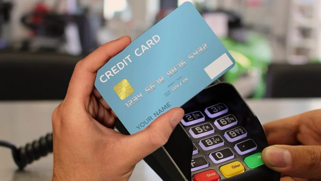 Retail checkout: customer holds a card to a payment terminal at a shop counter for a contactless payment
